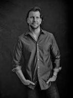 Black & White Image of author Carter Wilson wearing a button down casual shirt, rolled sleeves, and dark jeans